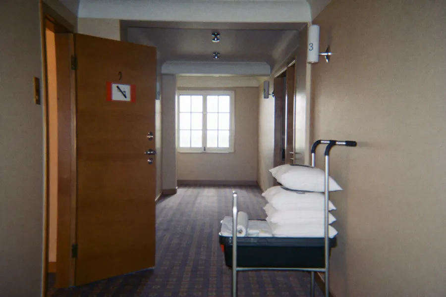 Couloir d'hôtel avec chariot de linge devant une chambre